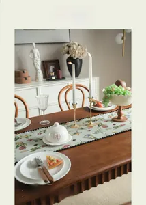 Detail of floral table runner with red berries and black lace trim on wooden dining table