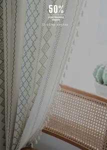 Détail du rideau nordique avec motifs géométriques verts et franges à pompons crème