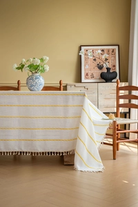 Close-up of cream French style tablecloth with yellow embroidery and tassel fringe