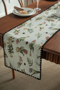 Detailed view of floral jacquard table runner with butterfly patterns and lace edges