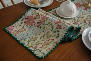Close-up of pink lily jacquard floral table runner with dark green scalloped edges