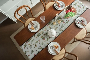 Close-up of jacquard floral table runner with blue flowers and black ball fringe trim