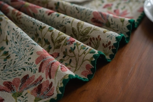 Detail of floral table runner featuring pink lily embroidery and green scalloped edges