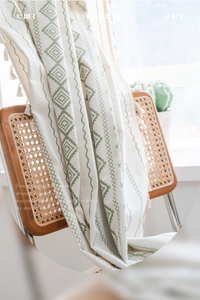 Détail de rideau boho nordique avec imprimé géométrique vert et glands faits à la main