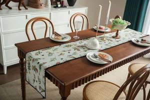 Detail of floral table runner with scalloped edges and butterfly motifs on wood table
