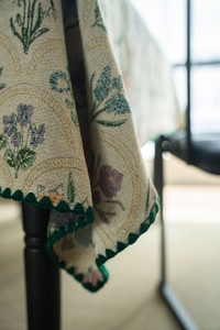 Detailed macro view of French vintage floral jacquard fabric with green scalloped edges