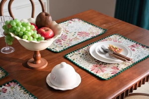 Close-up of floral embroidery on beige table runner with green scalloped edges