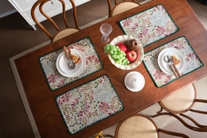 Detail of floral jacquard place mats with pink lily patterns and green crochet edges