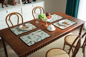 Detail of floral tapestry table runner with blue embroidery and black ball fringe trim