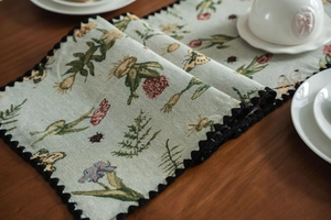 Close-up of floral jacquard table runner with scalloped edges on a wooden surface
