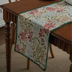 Floral jacquard table runner with pink lily patterns and decorative scalloped edges