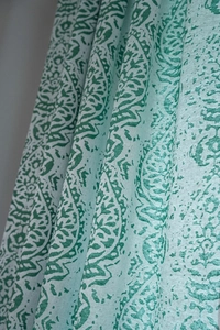 Detail of green paisley patterned curtain fabric with elegant draped texture and soft folds