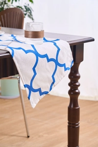 Close-up of blue Moroccan pattern table runner on dark wood table in home dining setting