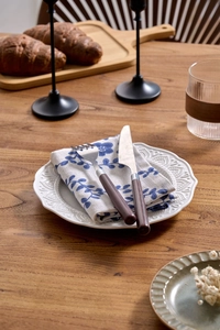 Detailed close-up of blue floral cotton linen napkin and rustic embossed ceramic plate