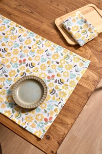 Macro detail of yellow floral pattern napkins on a rustic wooden table with ceramic plate