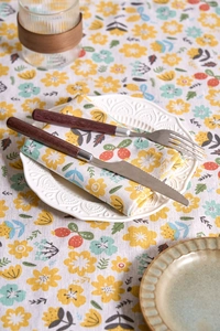 Detail of yellow floral cotton napkin set with rustic patterns on a dining table