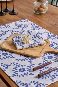 Detail of blue and white floral napkin and placemat set on a rustic wooden dining table