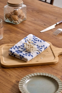 Detail of blue floral print linen napkin folded on a wooden tray for home dining decor