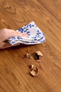 Close-up of cotton linen napkin with blue leaf print on a dark wooden table background