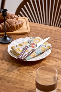 Detail of floral printed cotton napkin with stainless steel cutlery and wooden handle