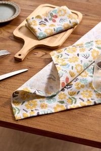 Detail of yellow daisy print floral napkin with rustic linen texture on wooden table