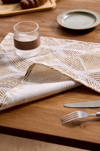 Detail of coffee brown wheat print on linen napkins displayed on a wooden table setting