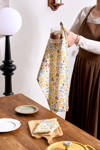 Detail of hand holding yellow floral cotton napkin for drying kitchen glassware