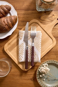 Detail of matte dark handle cutlery set with wood texture on white napkins