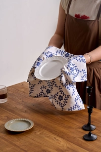 Close-up of floral linen napkin with blue vine print under a white ceramic plate