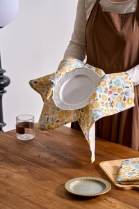 Detailed close-up of a floral napkin under a white ceramic plate on a dark wooden table