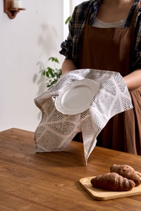 Detailed close-up of white embossed ceramic plate with grey geometric patterned napkin
