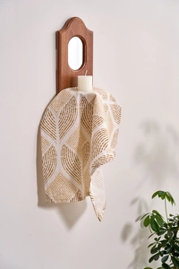 Close-up of modern beige fabric napkin with yellow leaf patterns on wooden mirror