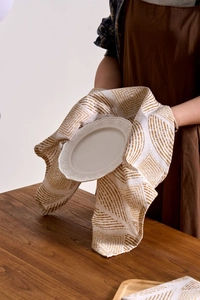 Detail view of modern wheat print fabric napkin wrapped around a white embossed plate