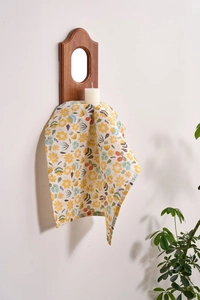 Close-up of yellow floral cotton linen napkin with neat edges on a wooden shelf