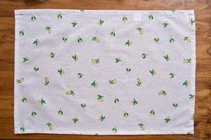 Detail of Nordic linen napkin with yellow lemon print on a rustic wood background
