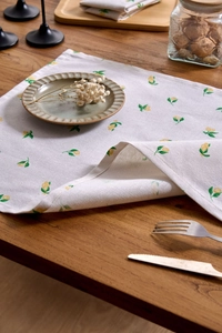 Close-up of lemon print fabric napkin with detailed stitching on a wooden dining table