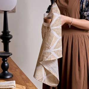 Modern fabric dinner napkin with brown geometric leaf print on cream linen backdrop