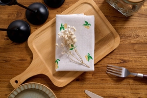 Detail of Nordic cotton linen napkin with lemon print on a wooden tray with cutlery