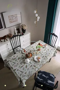 Detailed embroidery of floral and butterfly patterns on cream tablecloth with scallop edges