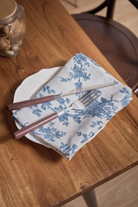 Detail of vintage blue rose print napkin with wood handle cutlery on a ceramic plate