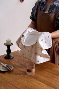 Detail of Nordic linen kitchen napkin with lemon prints on a warm wooden tabletop