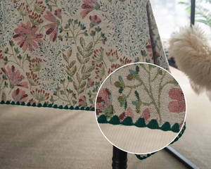 Detailed close-up showing vintage floral jacquard fabric and dark green pom-pom fringe