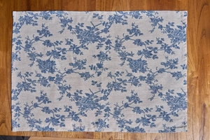 Detail of European floral placemat with blue rose prints on natural linen texture