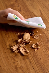 Close-up of lemon print cotton napkin cleaning crumbs on a wooden table surface