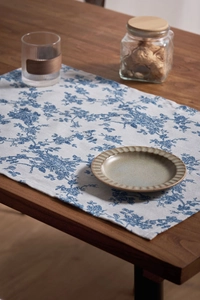 Detail of European floral table runner with blue roses on a dark wood dining table
