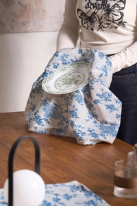 Close-up of vintage blue floral cotton linen napkin held by hands over a ceramic plate