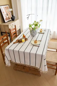 Close-up of minimalist cotton linen tablecloth with black embroidery and fringe details