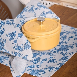 Vibrant yellow enamel cast iron Dutch oven with silver lid knob on floral napkin