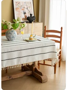 Detailed texture of cotton linen tablecloth with black geometric lines and tassel fringe