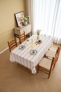 Detail of orange stripe embroidery and white tassel fringe on rectangle tablecloth